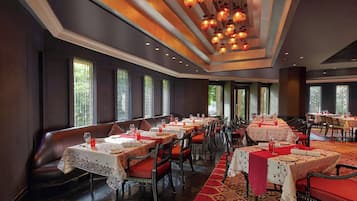 Un restaurante con varias mesas, sillas y una alfombra roja.