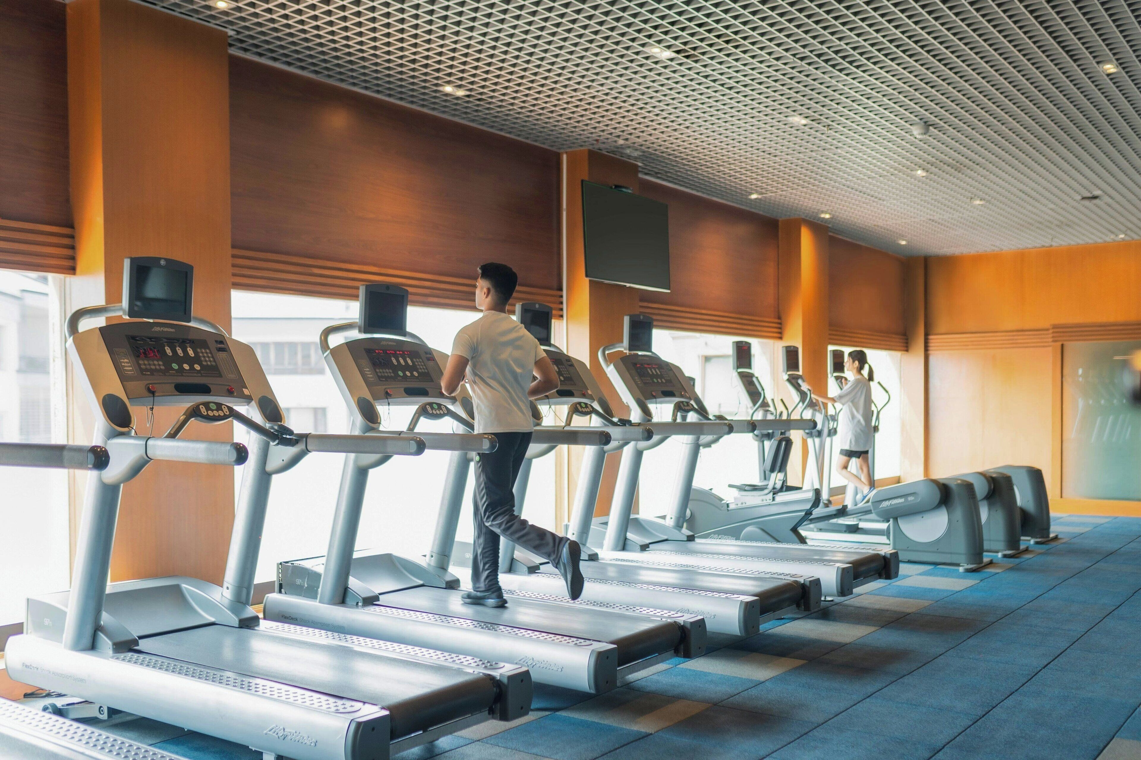 A gym with treadmills and a large screen on the wall.