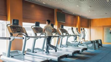 A gym with treadmills and a large screen on the wall.