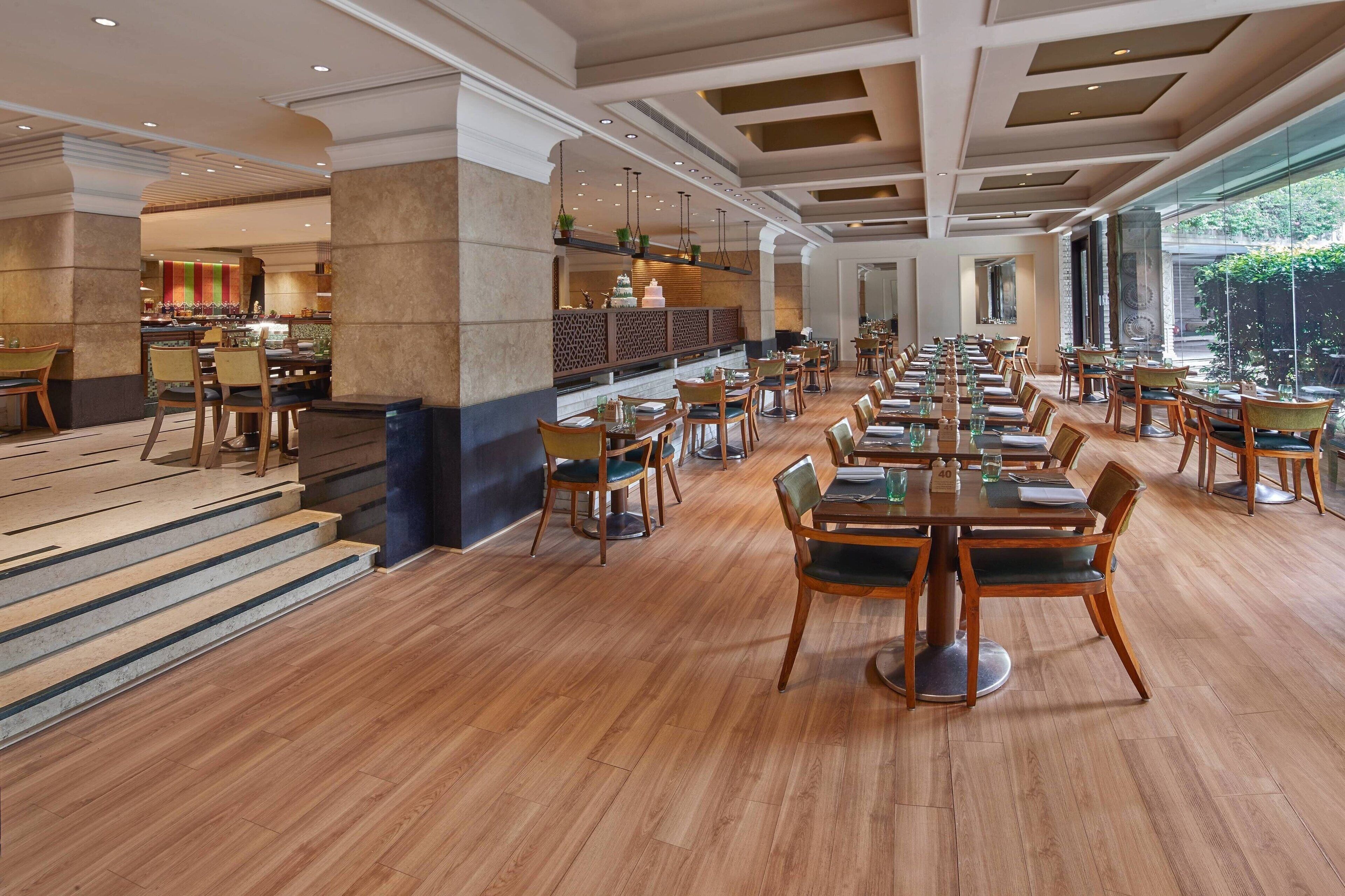 Un restaurante espacioso con techos altos, piso de madera y una larga mesa de comedor con sillas.