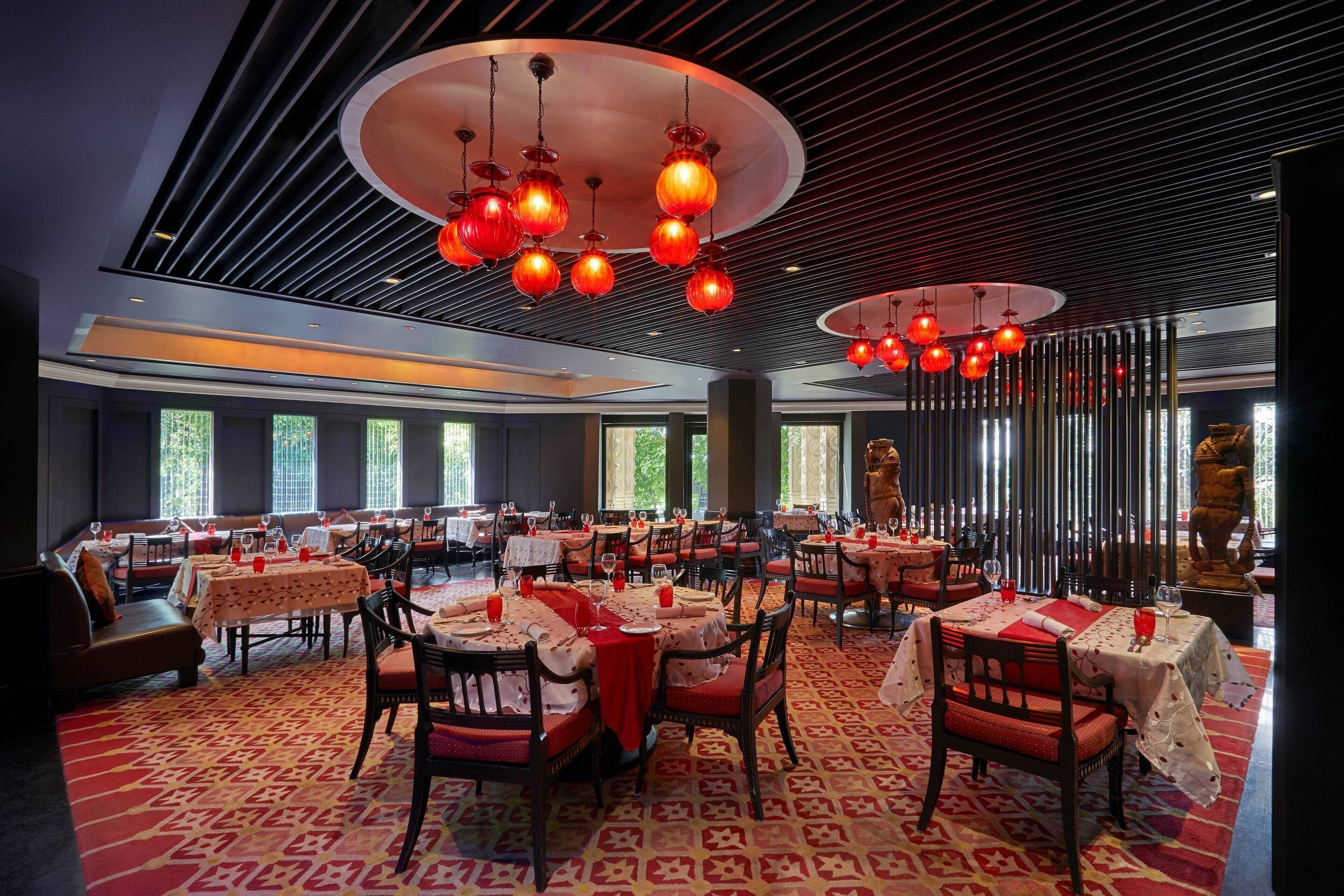 A restaurant with round tables, red chairs, and a patterned carpet.