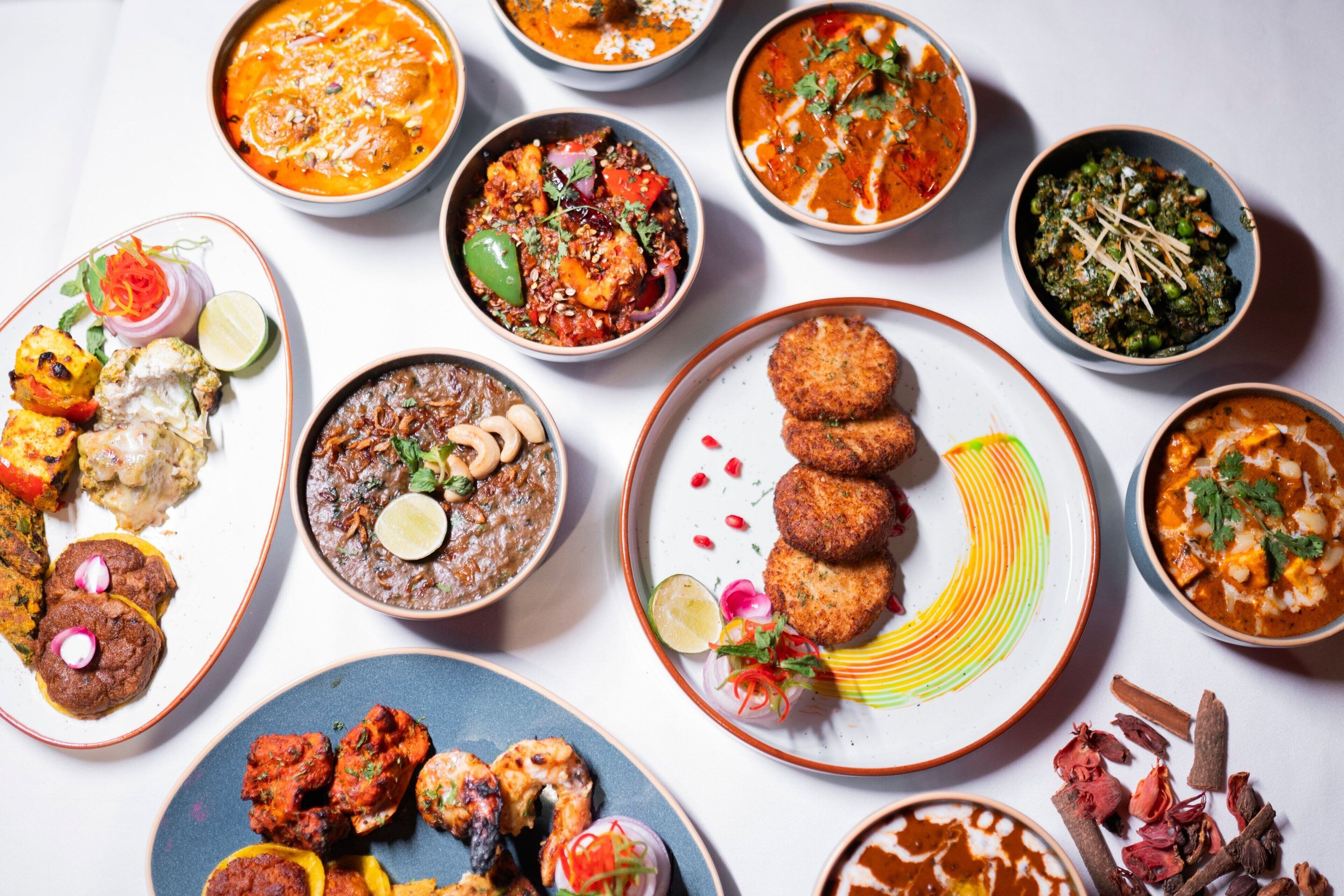 Diverse gerechten, waaronder curries, kebabs en een dessert.