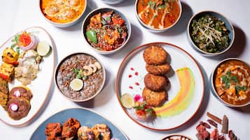 Diverse gerechten, waaronder curries, kebabs en een dessert.
