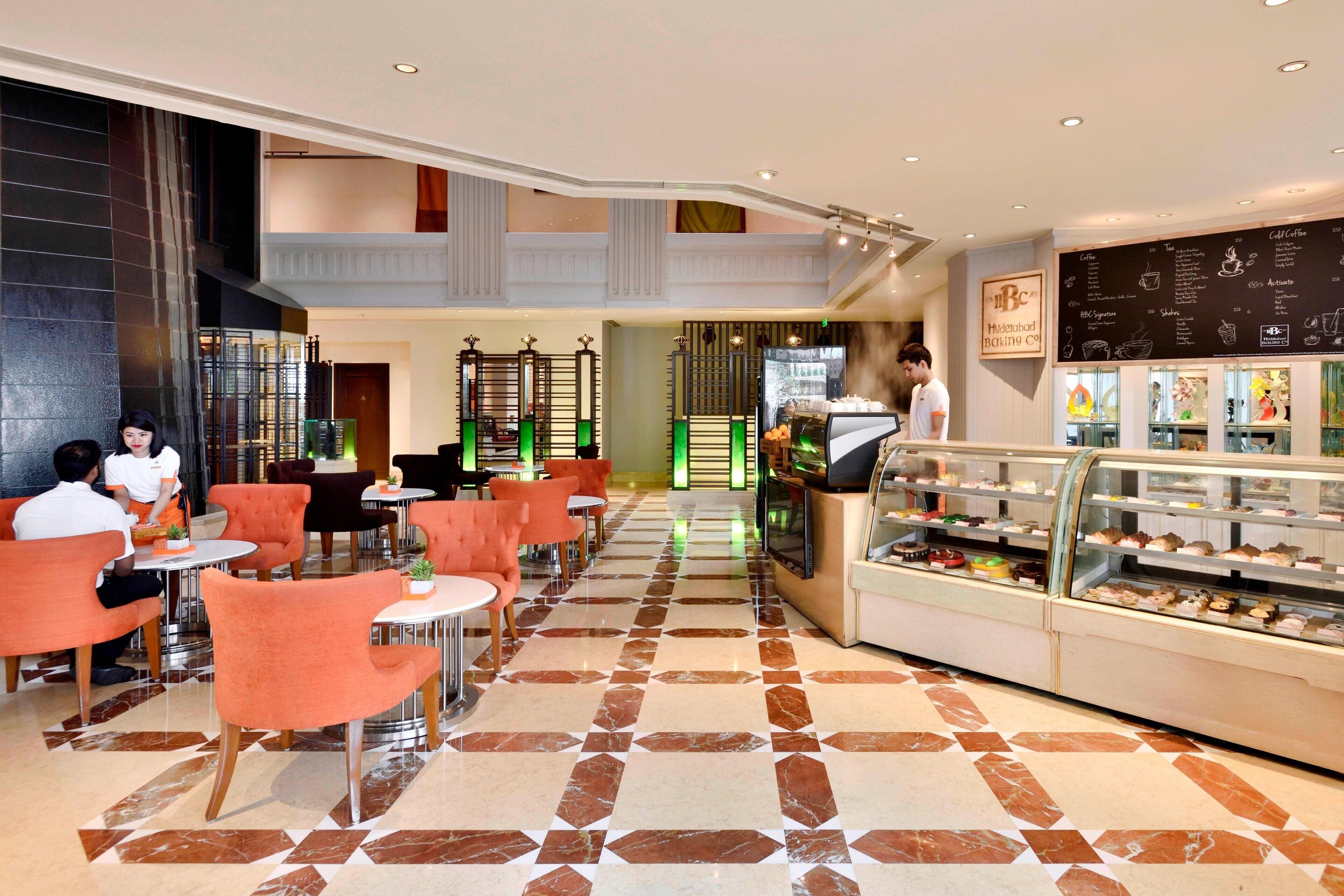 Un hall d’hôtel comprenant un comptoir de vente de produits de boulangerie, un espace salon et un comptoir d’enregistrement.