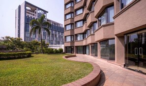 Een modern gebouw met een binnentuin, een palmpende en een verzorgd gazon.