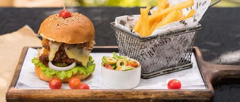 A burger with fries and a salad on a wooden board.