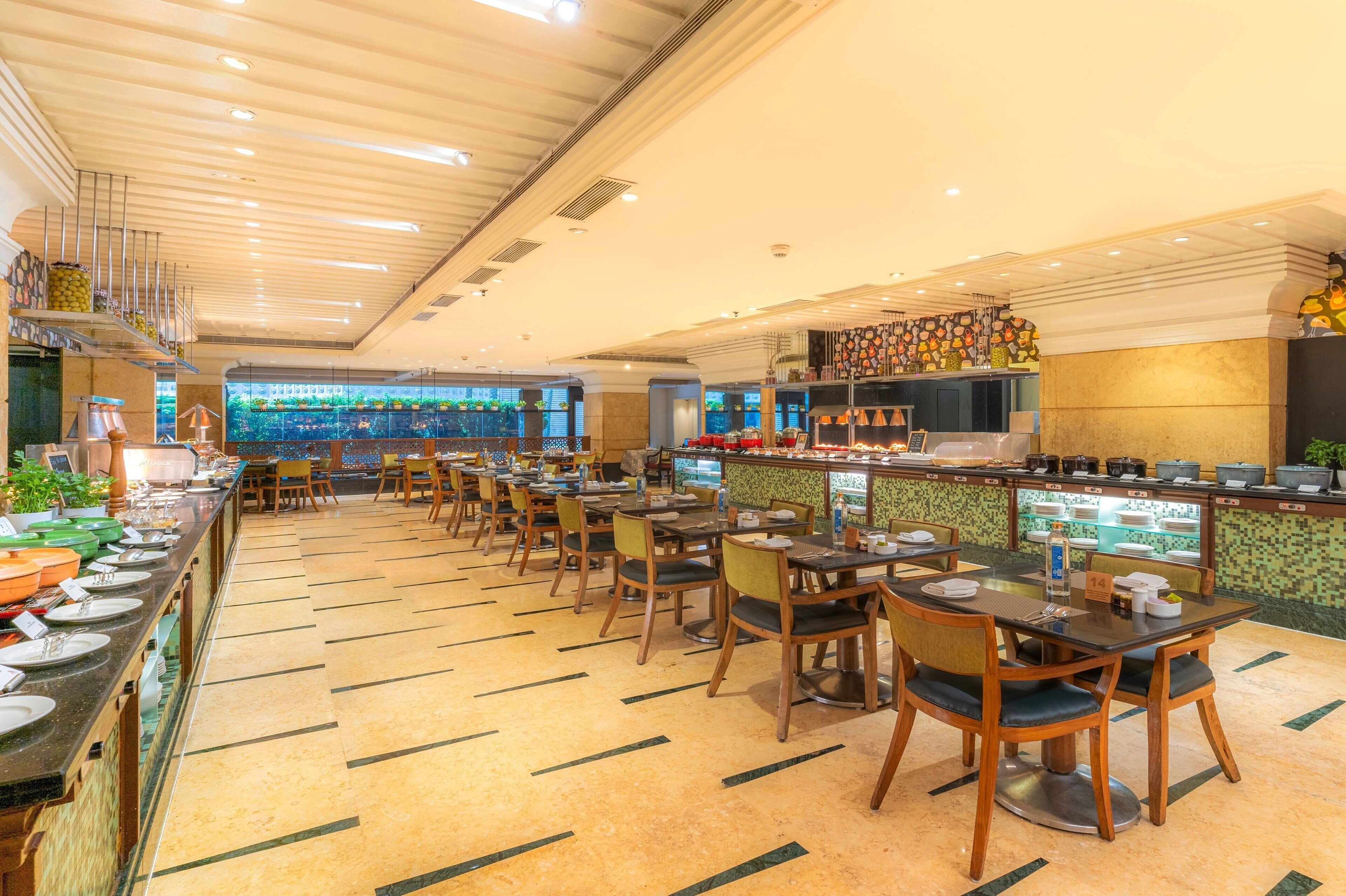 A restaurant with multiple tables and chairs, a buffet area with various dishes, and a counter with food items.