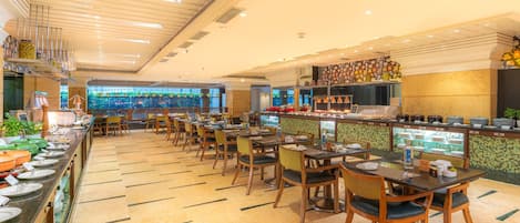 A restaurant with multiple tables and chairs, a buffet area with various dishes, and a counter with food items.