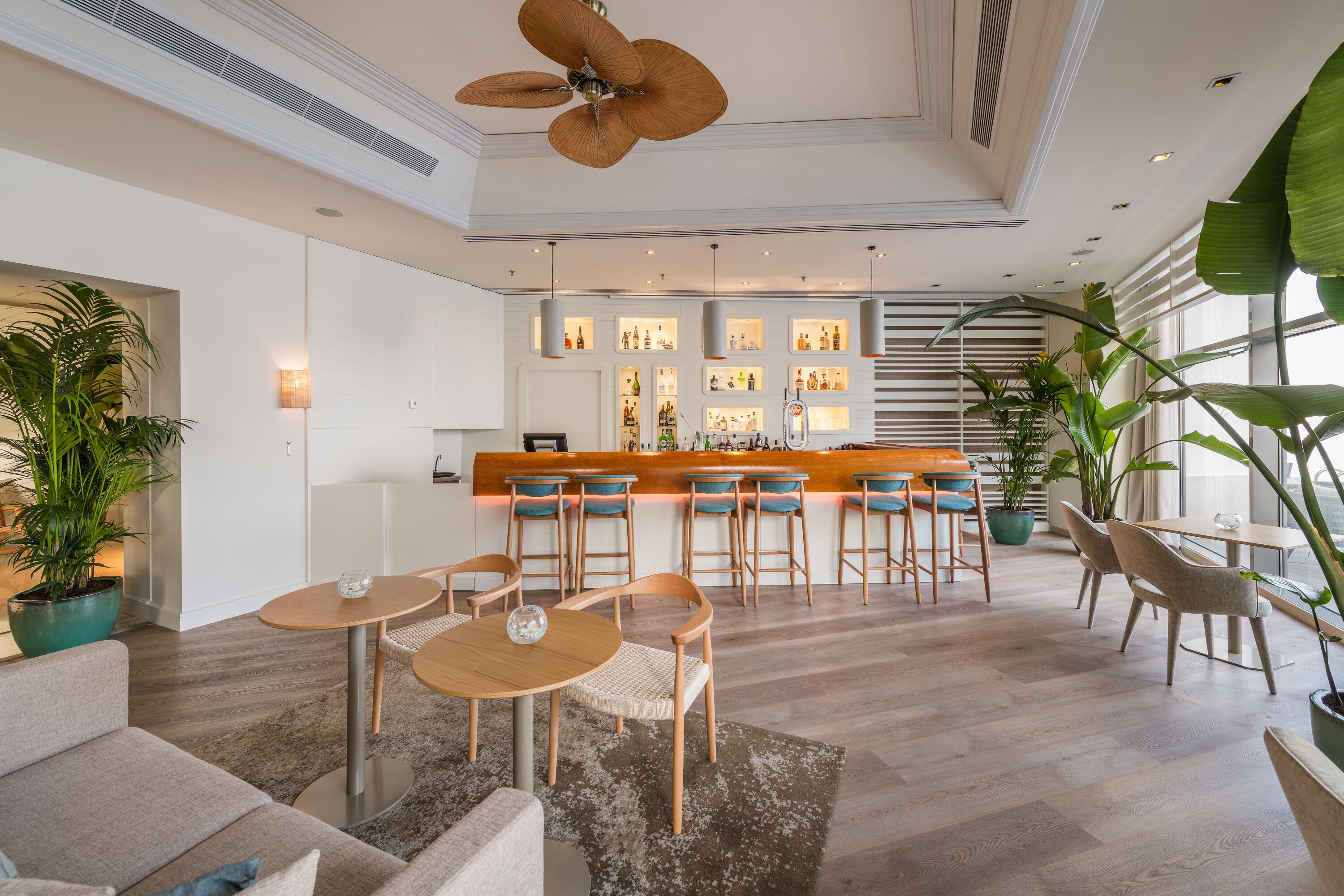A modern hotel lobby with a bar area, seating arrangements, and large windows.