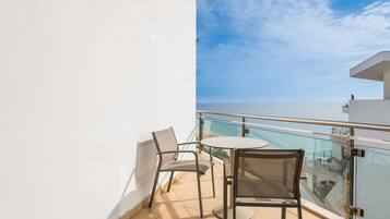 A balcony with two chairs and a table, overlooking a clear sky and a distant view.