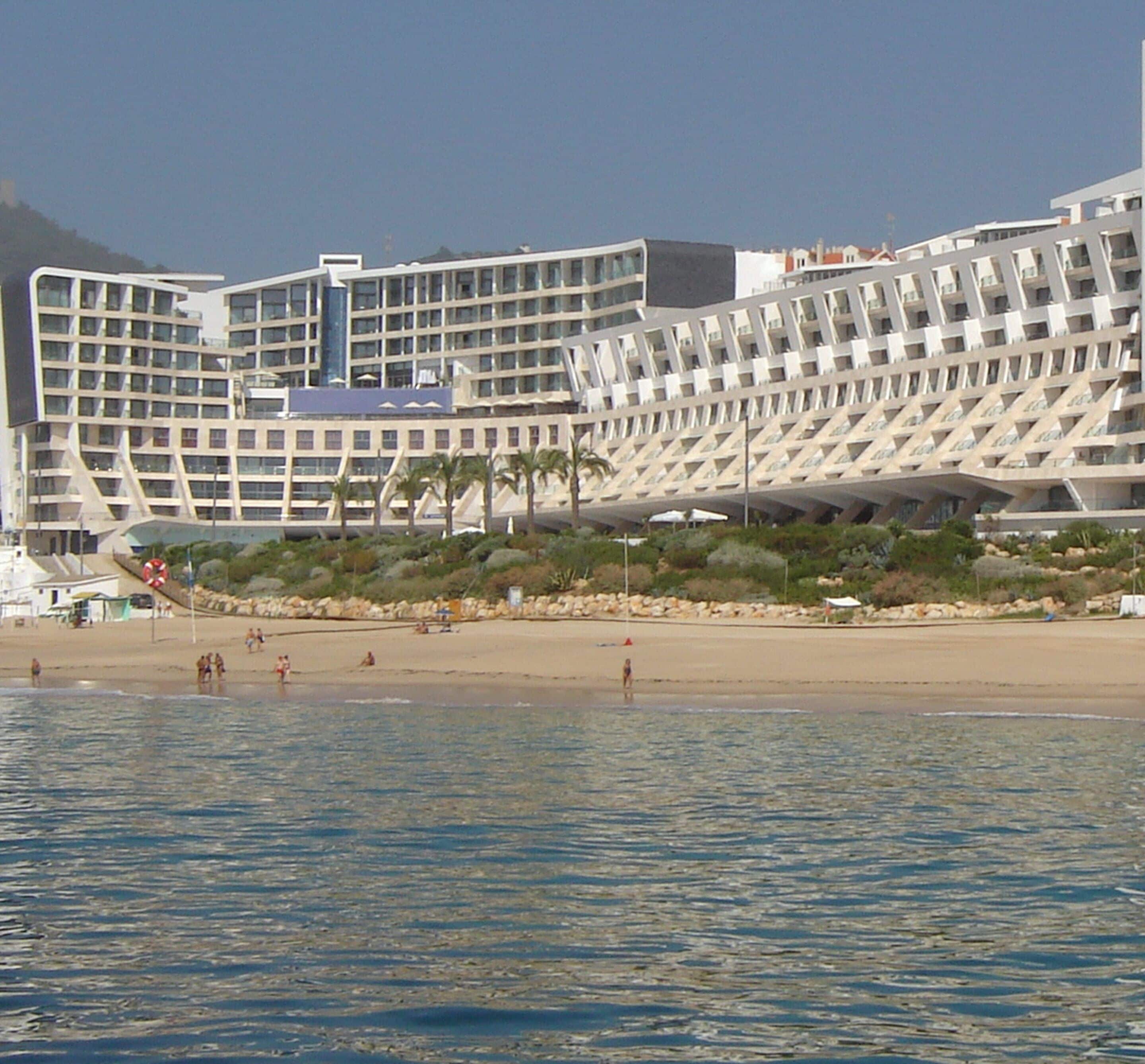 Et moderne hotel med et unikt arkitektonisk design, flere balkoner og beliggenhed ud til stranden.