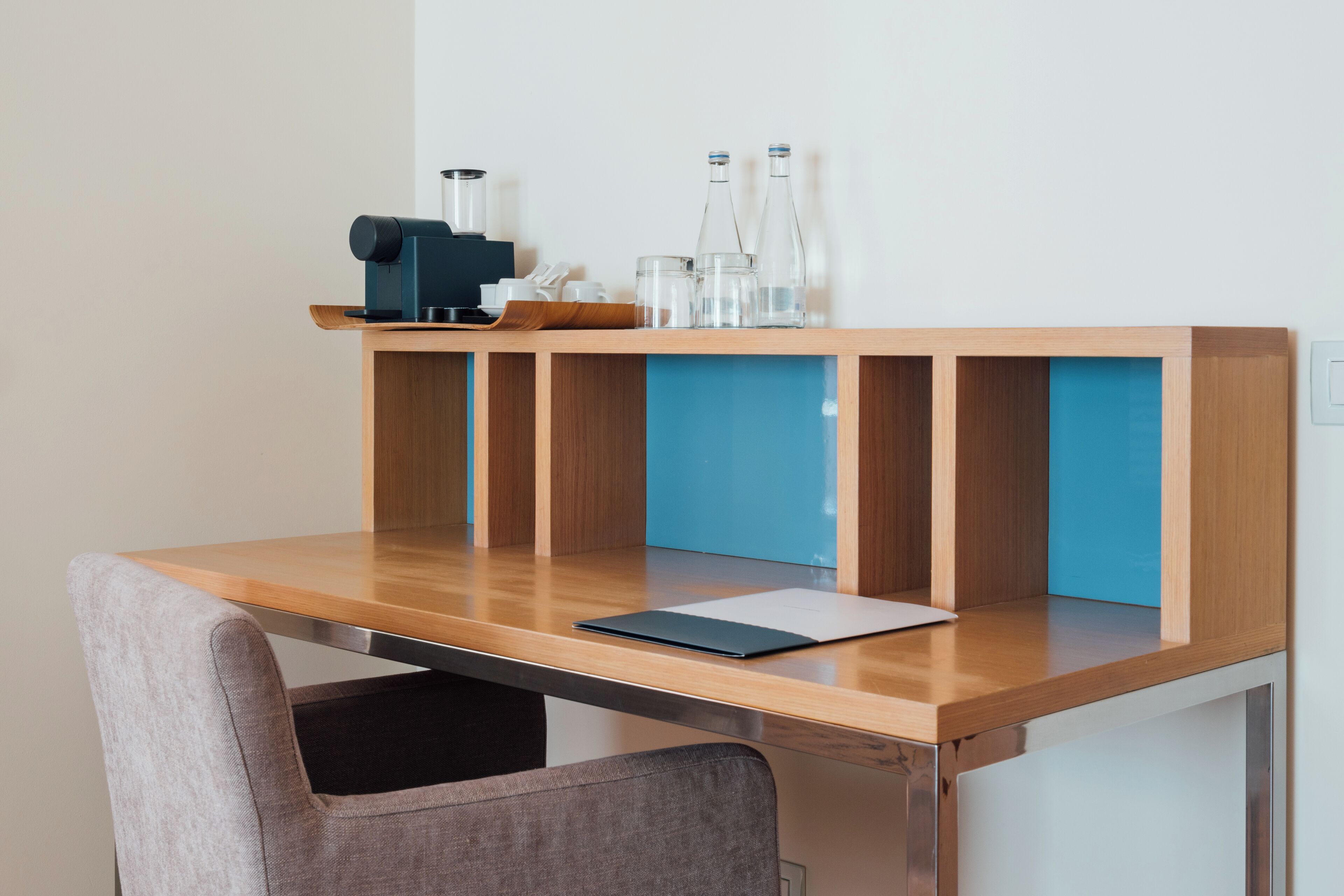 Una scrivania moderna con piano in legno e vani contenitori blu.