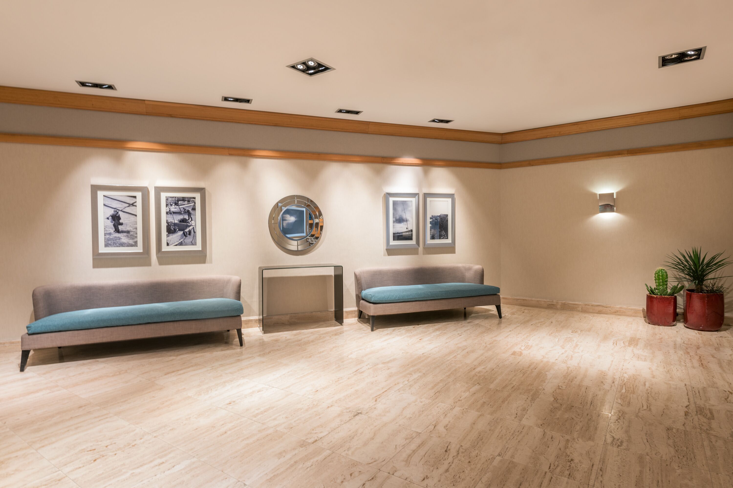 A spacious lobby with two sofas, a round table, and framed pictures on the walls.