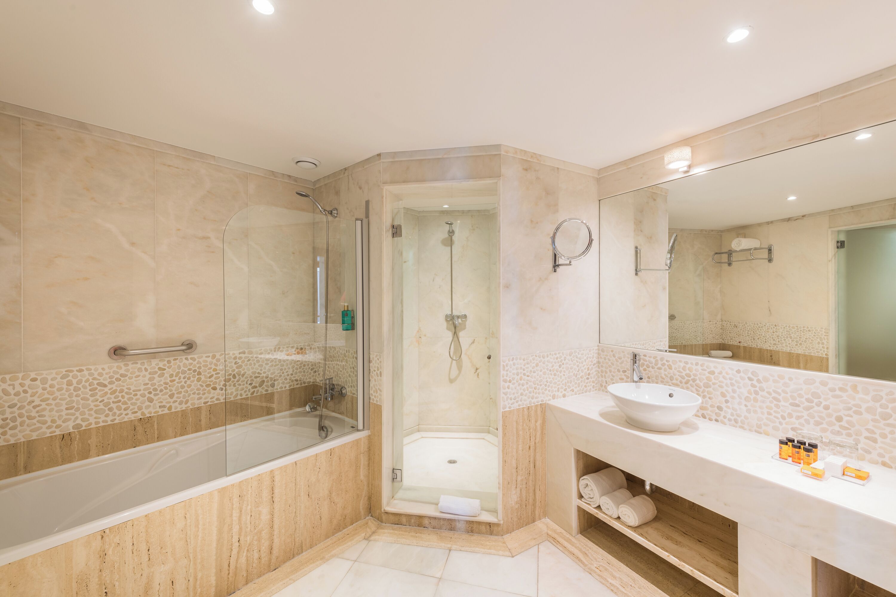 A modern bathroom with a glass-enclosed shower, a white sink, and a large mirror.