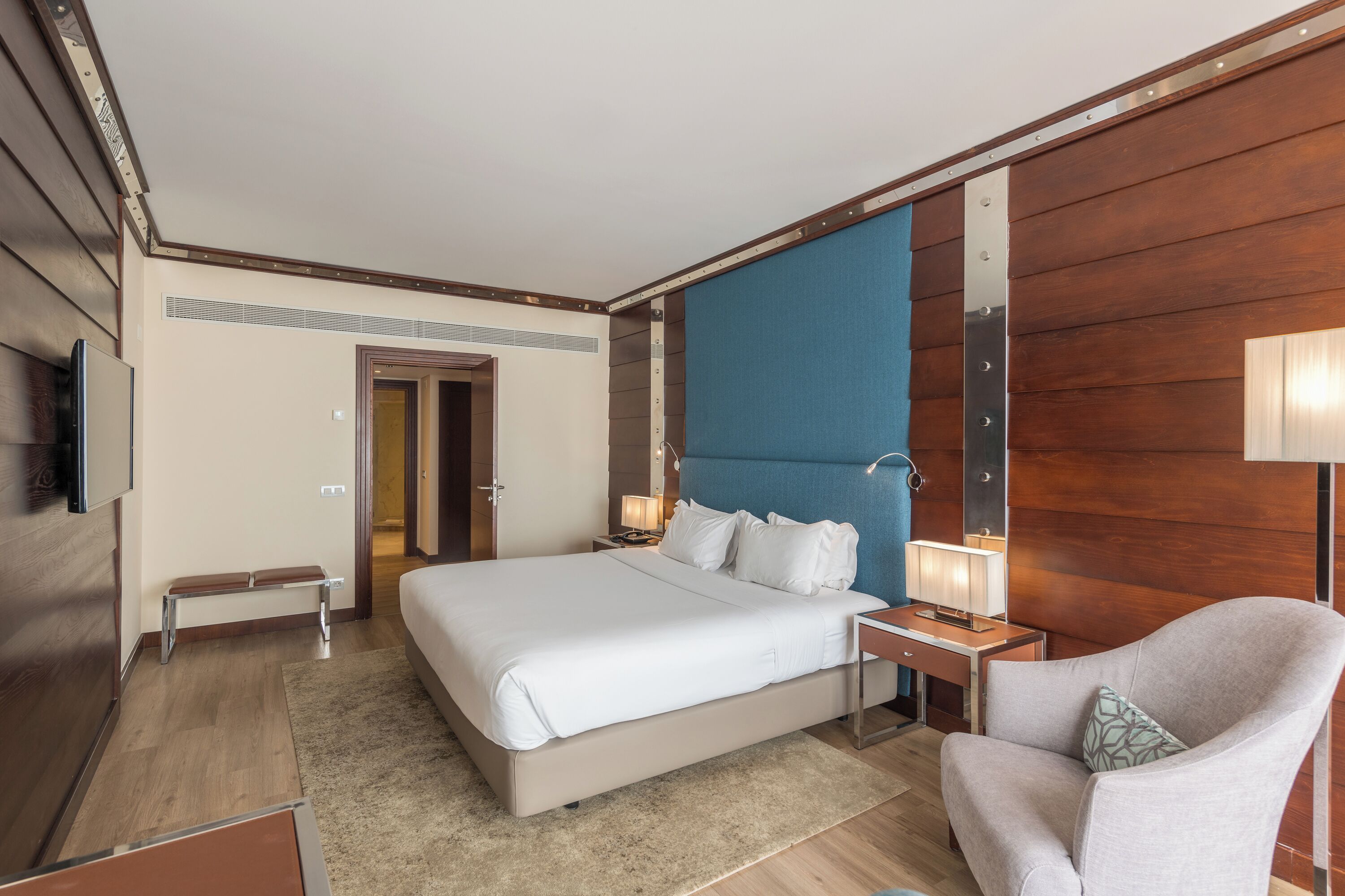 Een moderne hotelkamer met een groot bed, nachtkastjes, een stoel en een televisie.
