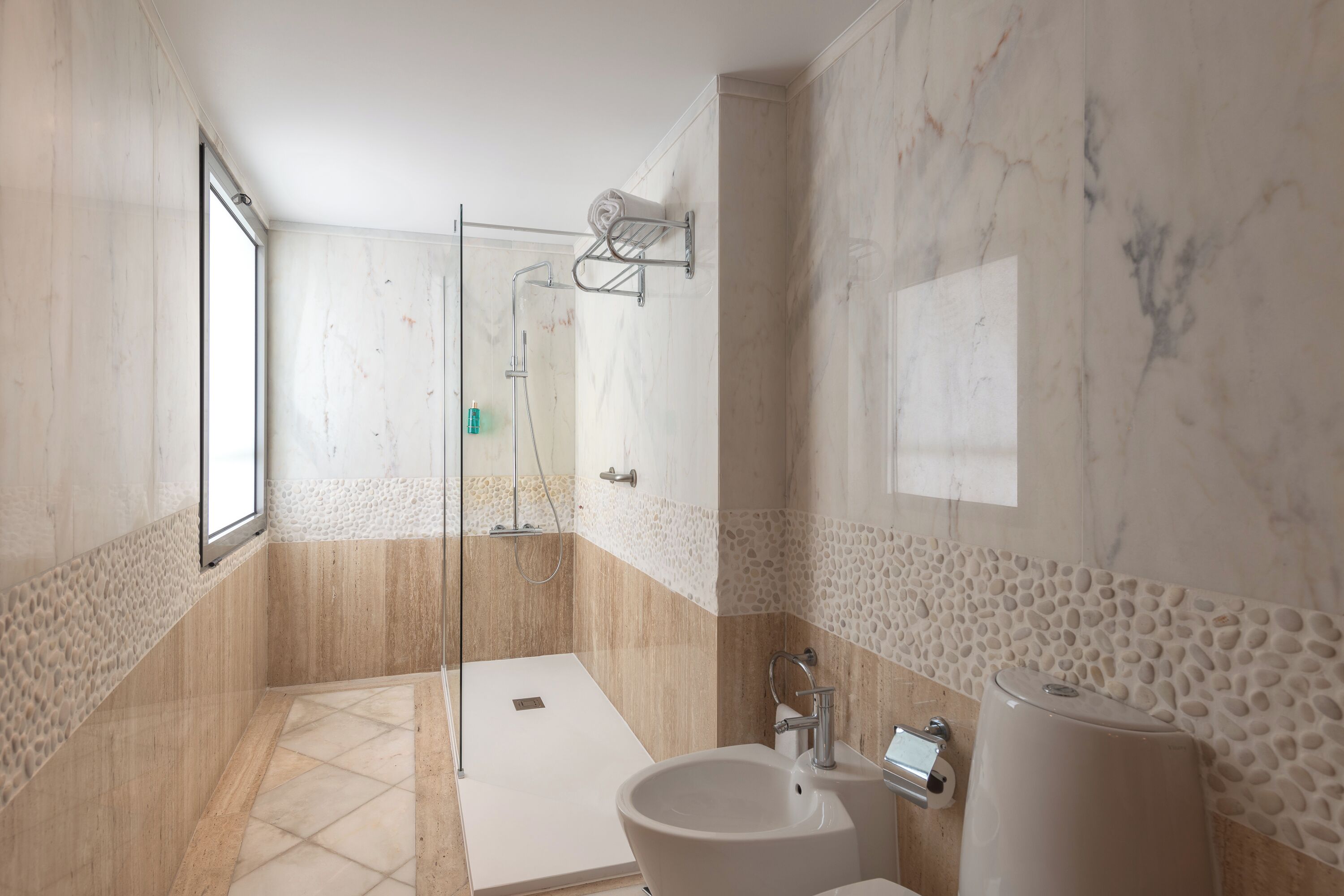 Ein modernes Badezimmer mit barrierefreier Dusche, Waschbecken und Toilette.