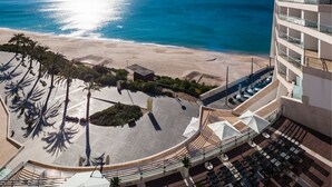A hotel with a beach view, outdoor seating, and a pool area.