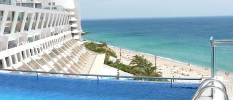 Una piscina techada, una piscina al aire libre, sombrillas