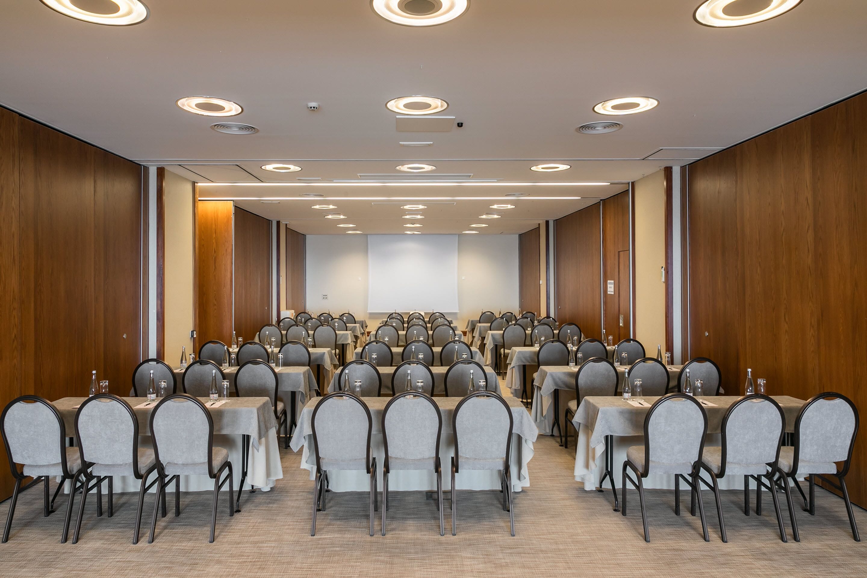 A conference room with rows of tables and chairs, equipped with water bottles and nameplates.
