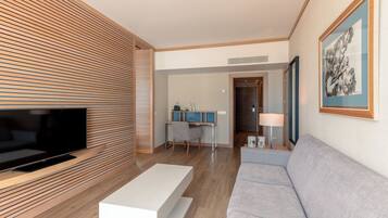 Una sala de estar moderna con un televisor de pantalla plana, una mesa de centro blanca, un sofá gris y una pared de listones de madera.