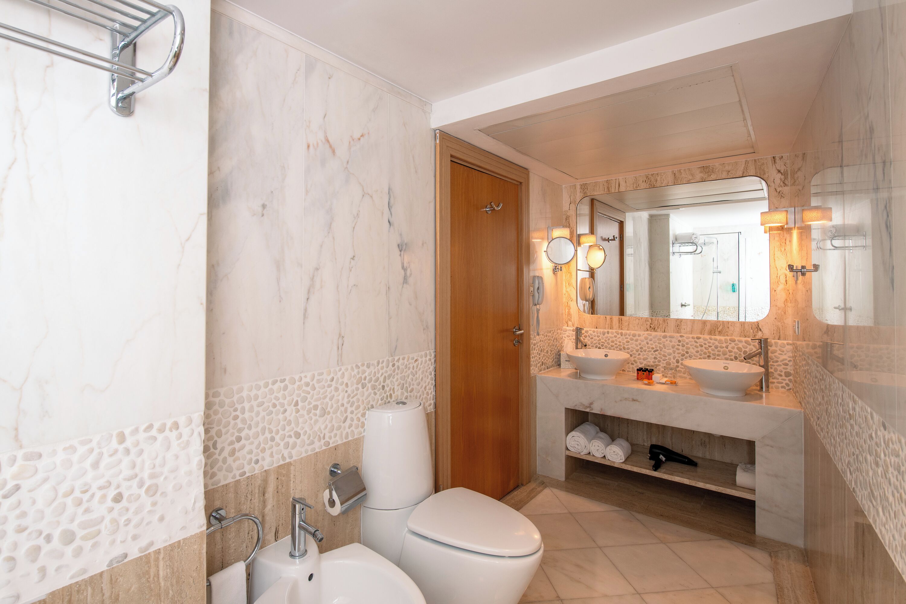 A modern bathroom with a marble vanity, a toilet, and a sink.