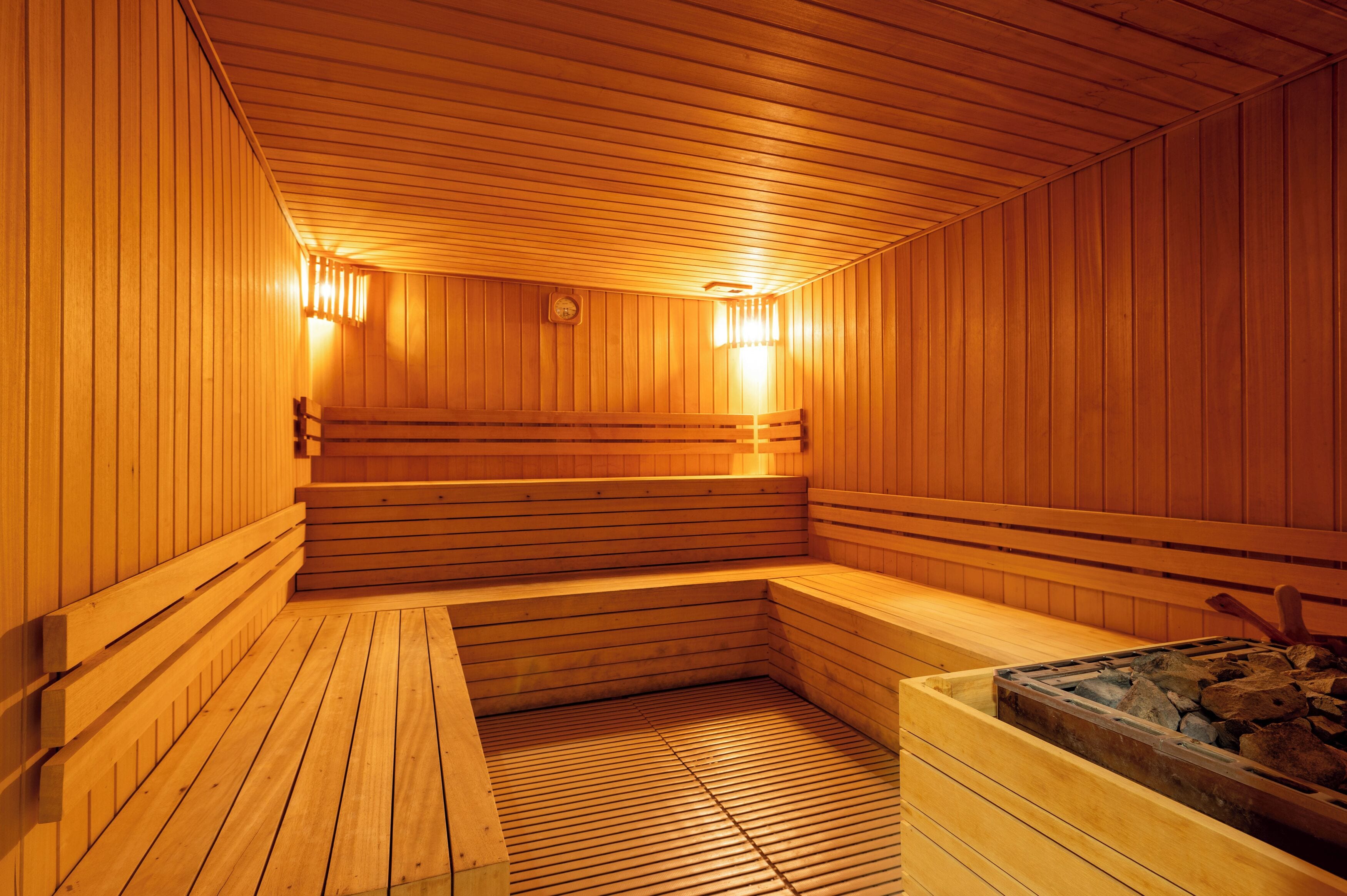 A wooden sauna with benches and a heated floor, featuring a wooden ceiling and walls.