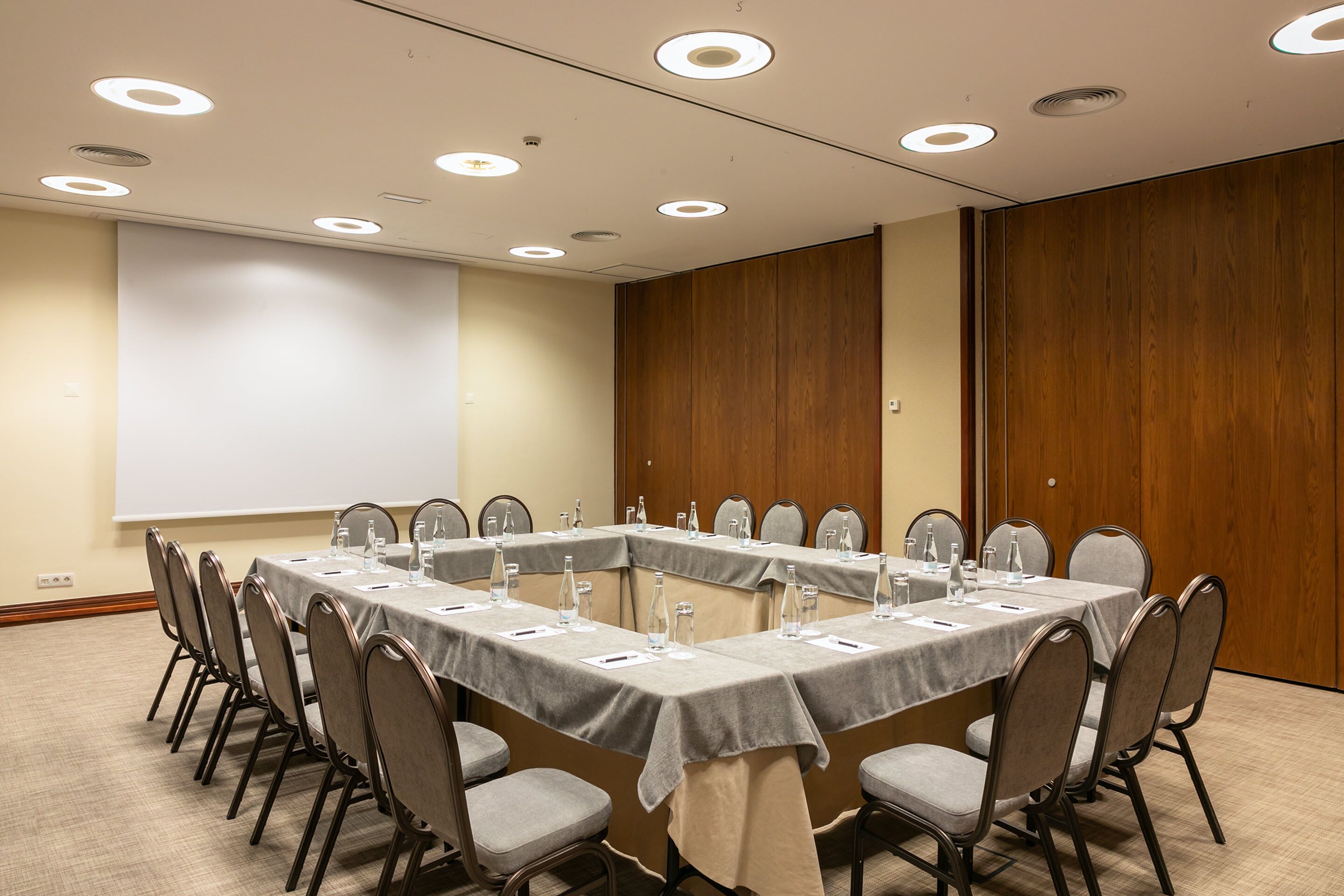 A conference room with a long table, chairs, and a projector screen.