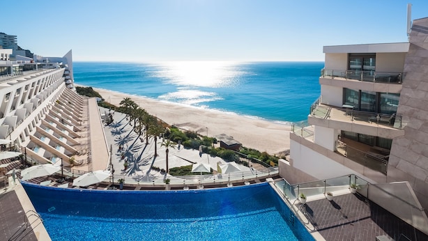 Um hotel moderno com piscina e vista para a praia e oceano.