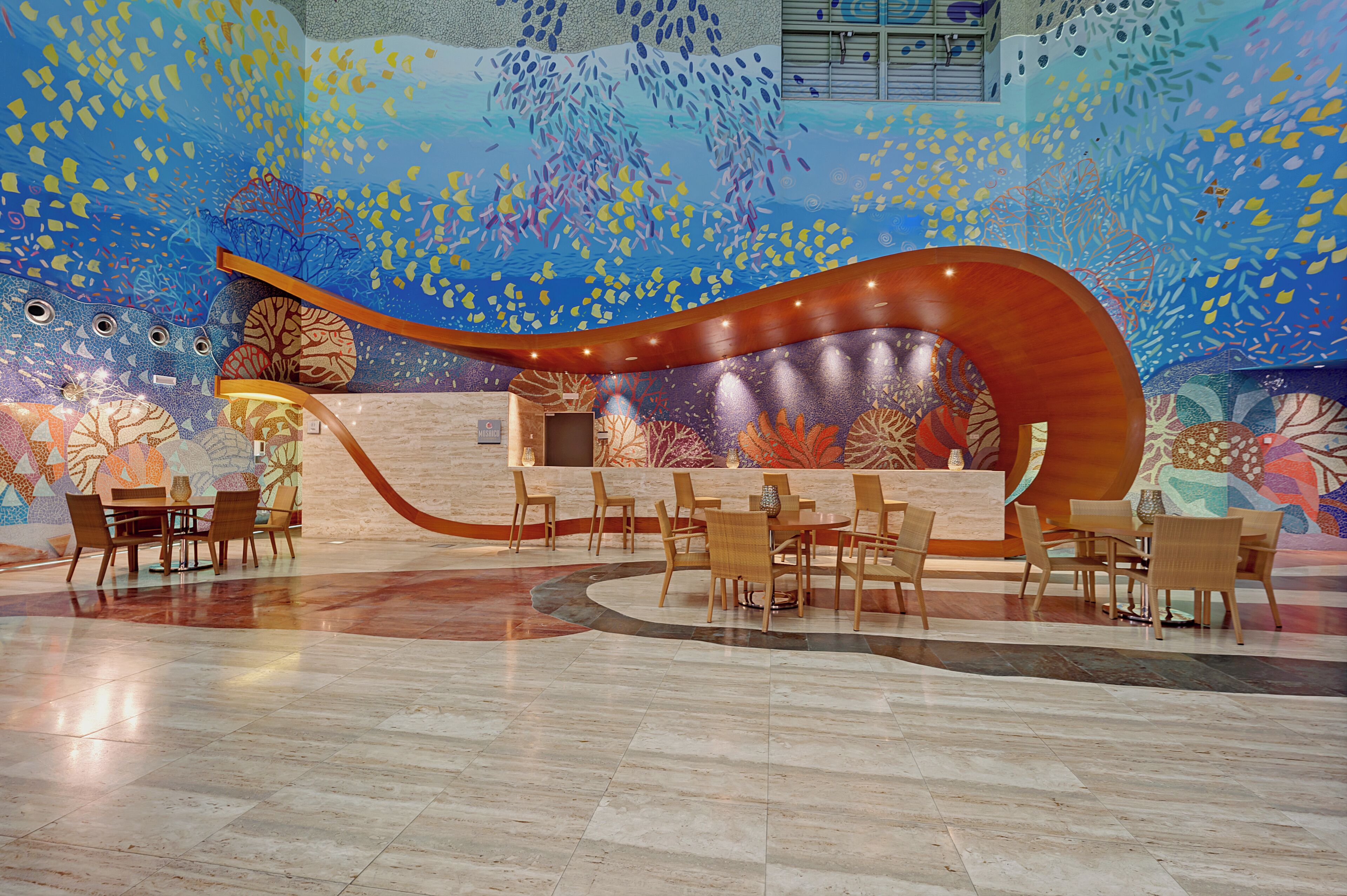 A reception area with a curved wooden desk, multiple chairs, and a tiled floor.