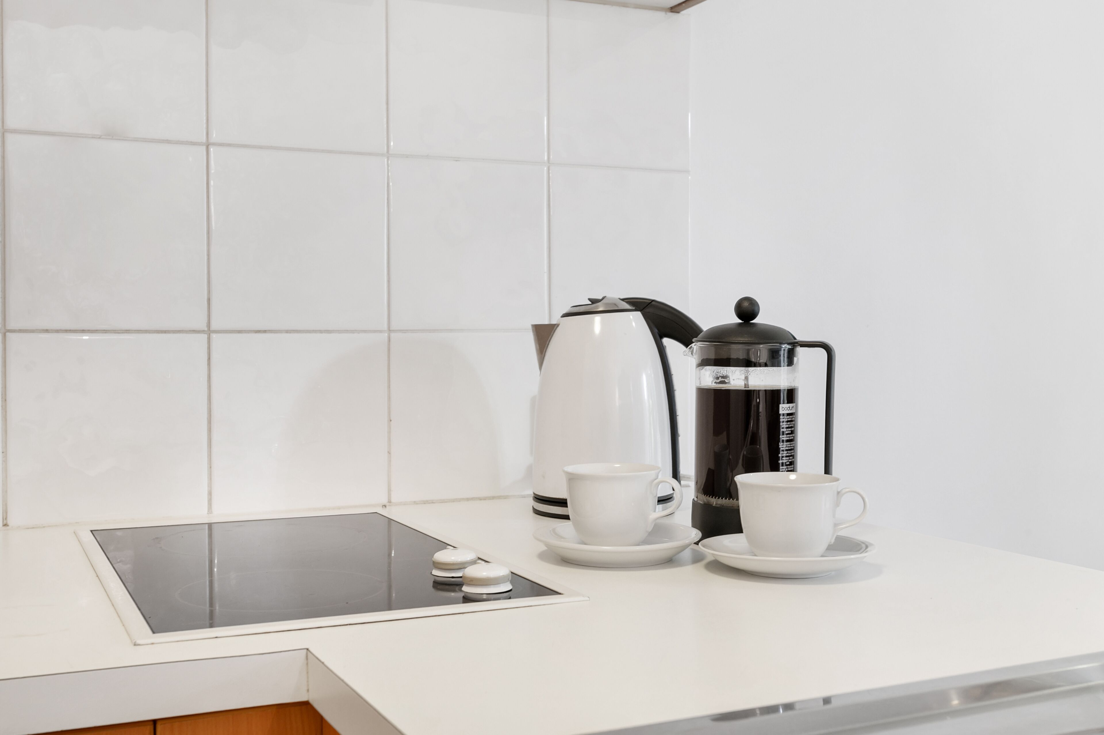 A clean, modern kitchen with a coffee maker, two cups, and a digital scale on the counter.