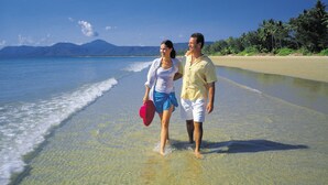 A couple walking on a beach with clear water and a mountain in the background. - Port Douglas Apartments - Adults Only Oasis (Port Douglas)