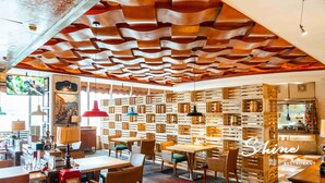 Interior de restaurante com design de teto moderno, divisórias de parede em madeira e diversos tipos de assentos.