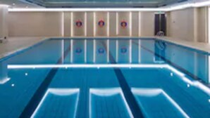 Uma grande piscina interior com design moderno, apresentando formato longo e esguio e uma faixa central para natação.