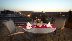 Mesa para dos con vistas a la ciudad, una botella de champán y mantel rojo.