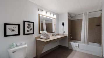 A modern bathroom with a toilet, sink, mirror, and shower.