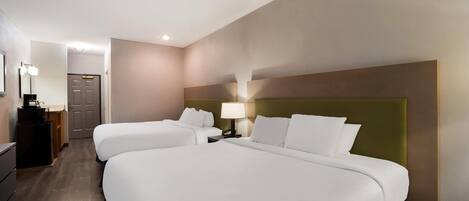 Una habitación de hotel con dos camas, un escritorio, una lámpara y un espejo.