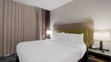Une chambre d’hôtel avec un grand lit, une table de chevet avec une lampe et une vue sur l’extérieur par la fenêtre.