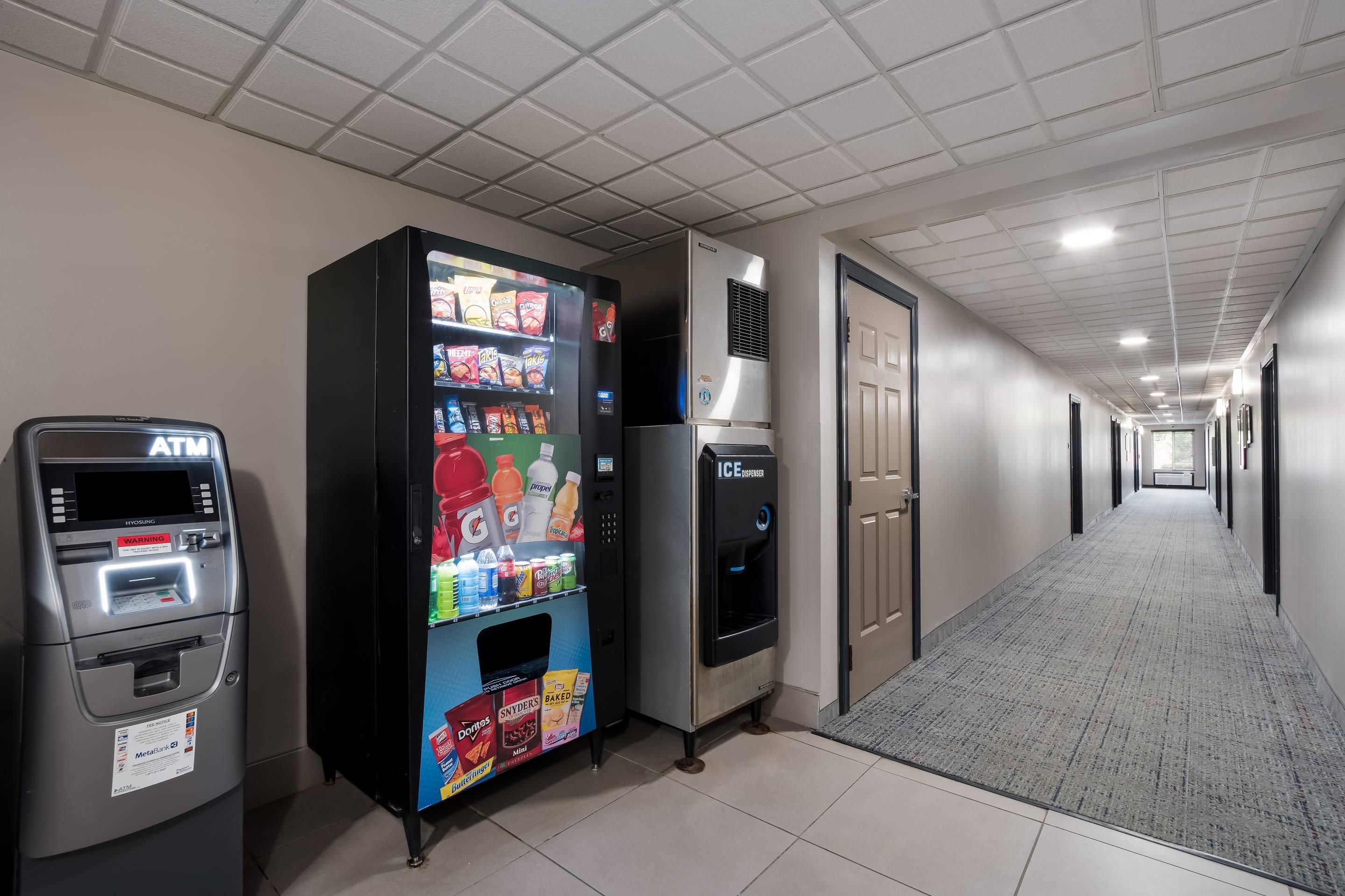 A hallway with an ATM, a vending machine, and an ice dispenser.