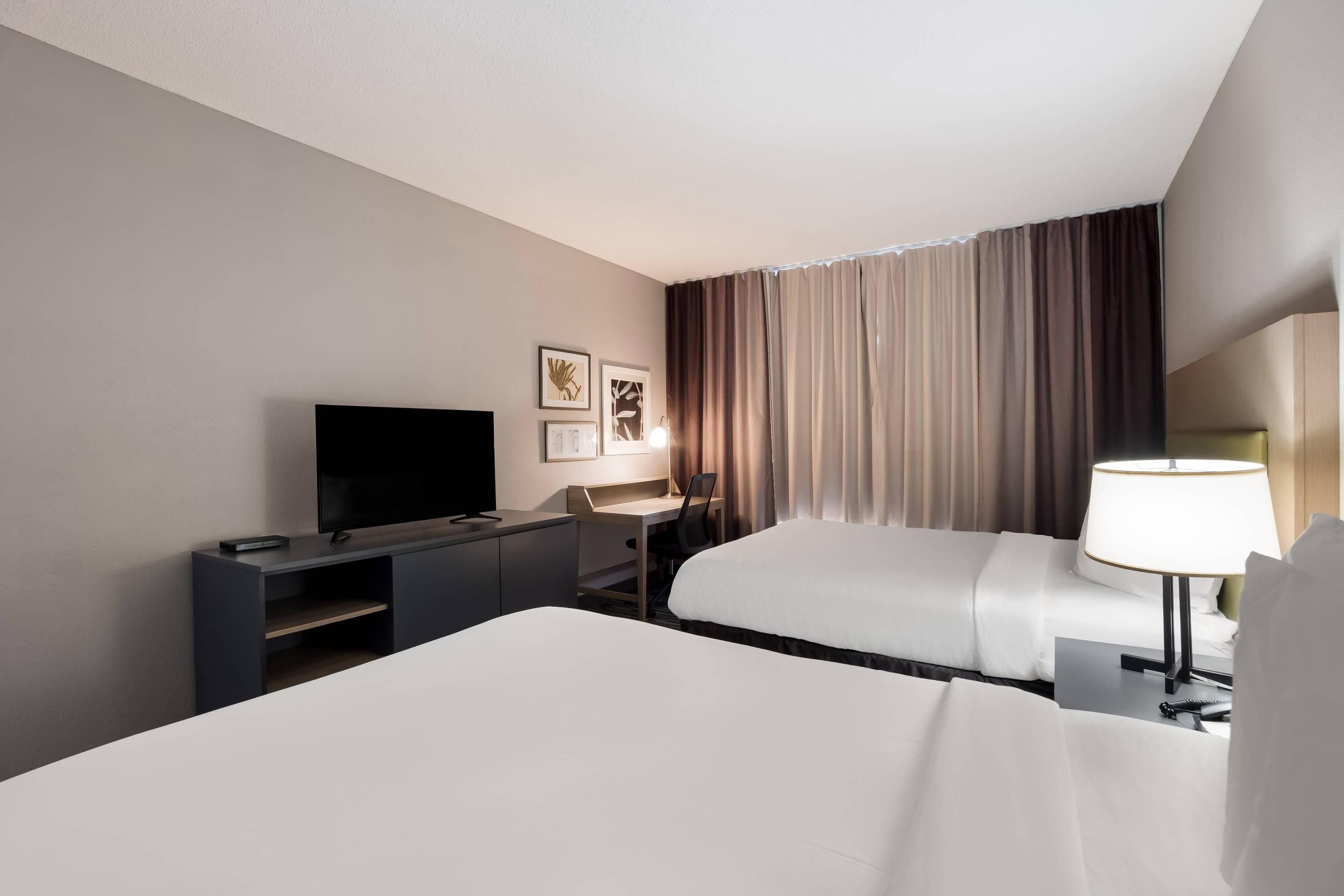 Une chambre d’hôtel avec un lit, un bureau, une télévision et une lampe.