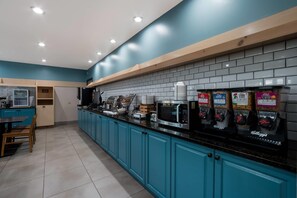 A modern kitchen with teal cabinets, a black countertop, and various appliances including a microwave and coffee machine. - Country Inn & Suites by Radisson, Augusta at I-20, GA (Augusta)