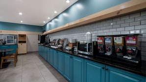 A modern kitchen with teal cabinets, a black countertop, and multiple appliances including a coffee machine and a microwave. - Country Inn & Suites by Radisson, Augusta at I-20, GA (Augusta)