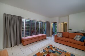 Un salon avec un canapé, un tapis à motifs et une porte-fenêtre coulissante donnant sur un balcon.