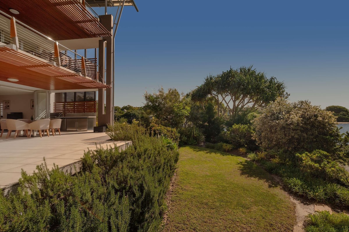 Een modern huis met een terras, zitplaatsen buiten en uitzicht op zee.