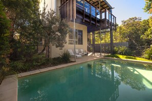 Une maison moderne dotée d’une piscine, d’un espace salon extérieur et d’une végétation luxuriante.