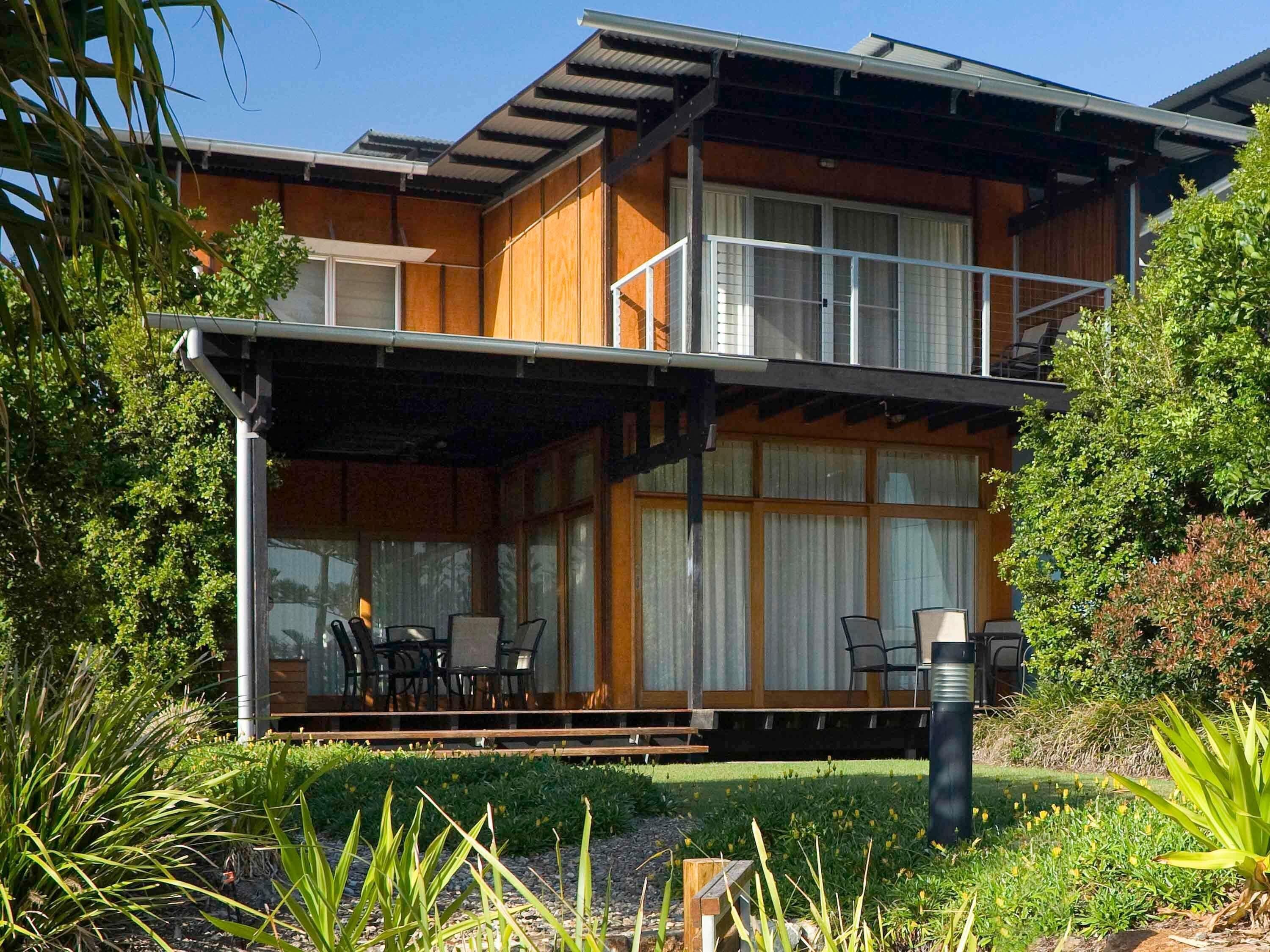 A modern two-story house with a covered porch, large windows, and a well-maintained garden.