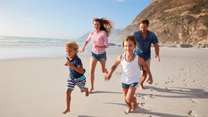 A family running on a sandy beach with a rocky cliff in the background. - The Sebel Twin Waters (Twin Waters)
