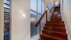 A wooden staircase with a metal railing, leading to a landing with a glass door. - The Sebel Twin Waters (Twin Waters)