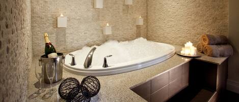 A modern bathroom with a freestanding bathtub, a champagne bottle, and candles.