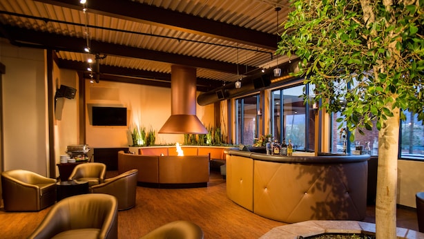 Un área de estar moderna con asientos de cuero, un bar y un amplio ventanal con vistas al exterior.