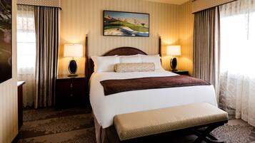 A hotel room with a large bed, two bedside lamps, a painting on the wall, and a patterned carpet.